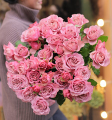 Young woman with a gift bouquet of pink spray roses, mono bouquet of roses. Young woman holding fresh bouquet of roses.