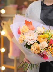 Flower shop. Beautiful bouquet of mixed flowers in woman's hands. the work of the florist at a flower shop. Bright color. Fresh cut flower.
