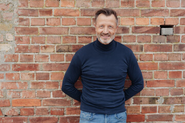 Middle-aged man posing against a brick wall
