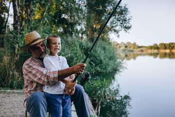 boy fishing on the lake with his grandfather