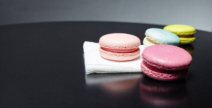 French macaroon cake. Colorful macaroons on paper napkin on dark table with copy space