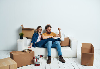 Fototapeta na wymiar A man and a woman are sitting on the couch near the boxes with things moving the interior of the room