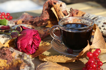 Autumn still life with a rose, a cup of coffee and a warm knitted scarf