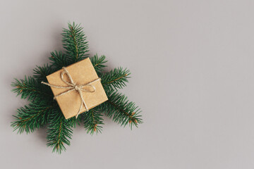 Craft gift box with spruce branch on a grey background. Holiday eco-friendly concept.
