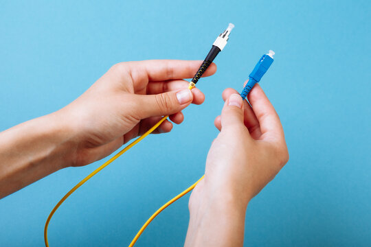 woman's hands hold SC and FC connector fiber optic patch cord single mode on blue background