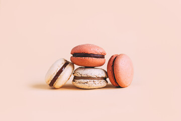 Tasty french macaroons on a pink pastel background.