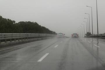 Cars driving along a wet highway in rainy weather