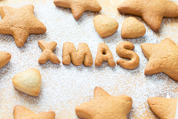 Cookies in the form of XMAS lettering in the form of gingerbread cookies stars on the background of a rolling board with powdered sugar. Concept for New Year, Noel food, card. Homemade food.
