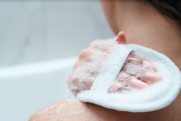 Woman's shoulder close-up. The girl lathers her shoulder with a washcloth, sits in the bath. Skin and body care. Relaxation. asparagus procedures