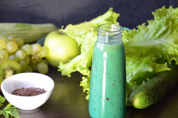 Green fruits and vegetables on a black background. Kiwi, green grapes, lettuce, zucchini, cucumbers, green apple, parsley with spinach top view selective focus