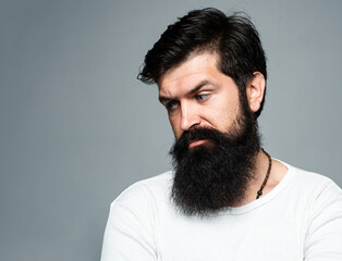 Obraz premium Portrait of confident serious man has beard and mustache, looks seriously, isolated. Hipster guy models in studio. Businessman thinking with expression looking. Handsome male model, closeup face.