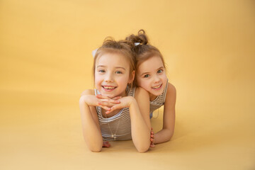 Fototapeta na wymiar Image Of Two Happy Sisters Having Fun on yellow background