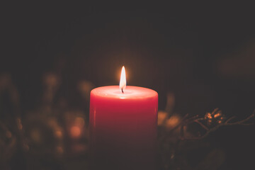 Merry Christmas concept with red burning candle on dark background