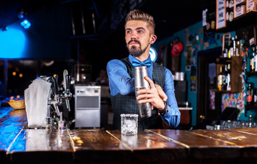 Experienced bartender is pouring a drink behind the bar