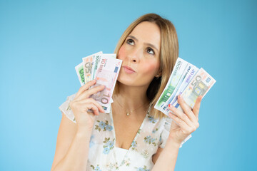 young woman standing isolated over blue background with money