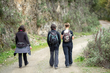 Group of three, two women and a man, walking in nature.