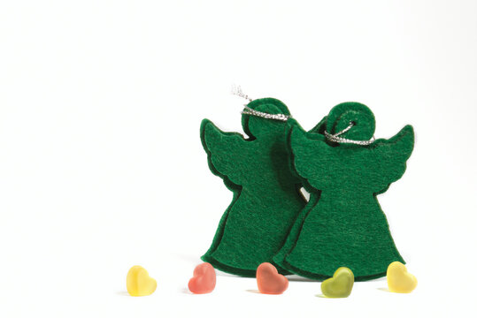 Greeting a Christmas Card for xmas & New Year holiday season. The frame with a two green felt angeltoys and copy space for your text. Soft focus.In the foreground are five hearts.  