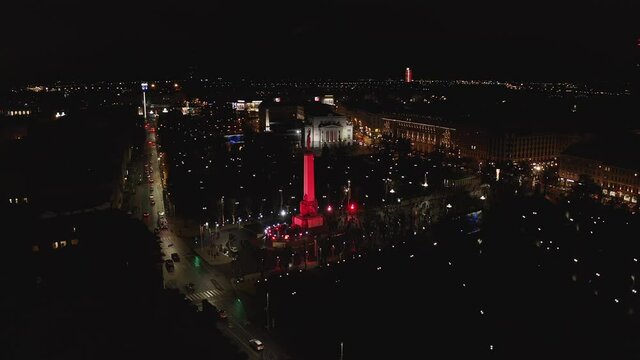 Monument of freedom at night in Riga, Latvia during Staro Riga event. Milda - Statue of liberty holding three stars over the city illuminated in different colors. 
