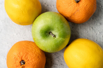 Top view on green apple granny smith with oranges and lemon on marble table - healthy organic eating fresh food rich in vitamins