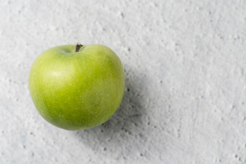 One granny smith green apple on marble bright table with copy space