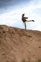 Girl doing balance gymnastics exercise on top of sand hill