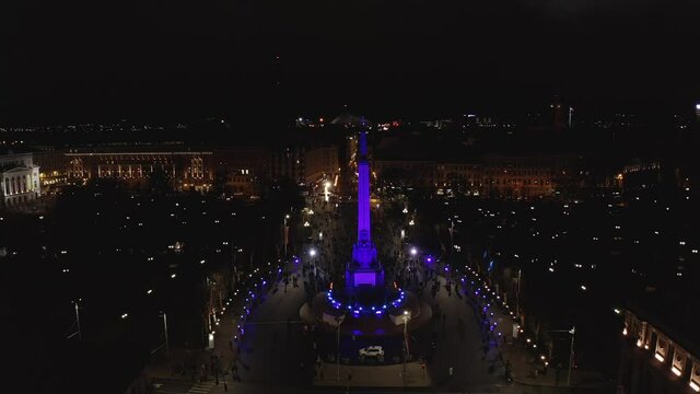 Monument of freedom at night in Riga, Latvia during Staro Riga event. Milda - Statue of liberty holding three stars over the city illuminated in different colors. 