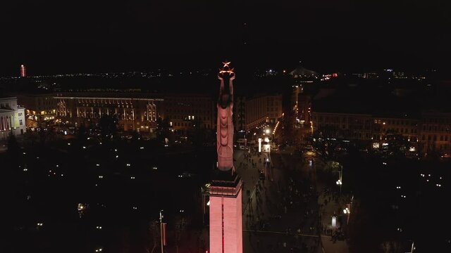 Monument of freedom at night in Riga, Latvia during Staro Riga event. Milda - Statue of liberty holding three stars over the city illuminated in different colors. 
