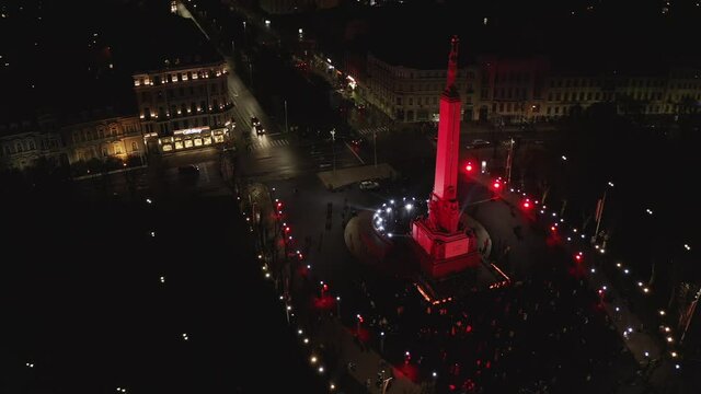 Monument of freedom at night in Riga, Latvia during Staro Riga event. Milda - Statue of liberty holding three stars over the city illuminated in different colors. 