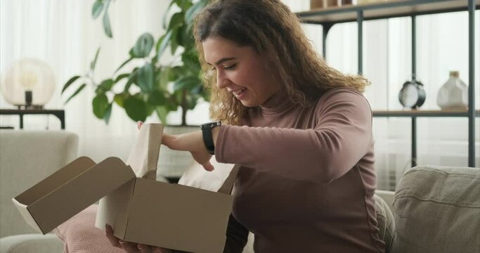 Happy woman opening gift parcel at home