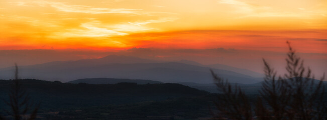 Beautiful sunset panorama photo over the field and the top of mountains.