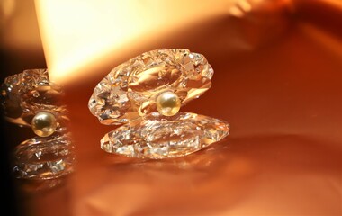 A pearl inside shell shiny crystal show piece isolated on beautiful golden background and the reflection also seen  