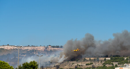 Fototapeta na wymiar fire starts on the hills of Marseille, near Marignane airport. yellow fire-fighting plane is going to throwing water on it. 