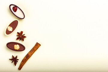 Chocolate candies with nuts and cinnamon sticks on a light background. Top view, place for text