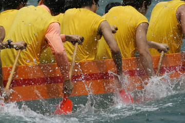 close up on paddles of a dragon boat team while racing