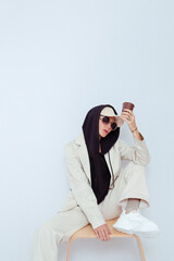 Model in white studio. Trendy beige casual outfit with black hoodie accent.  Cap, sunglasses, Denim Suit Jacket and Pants. Street Urban Style. Fall winter season.  Fashion lookbook concept