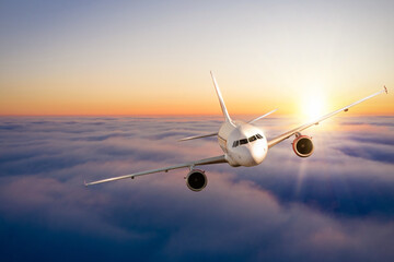 Fototapeta na wymiar Commercial airplane flying above clouds in dramatic sunset light.