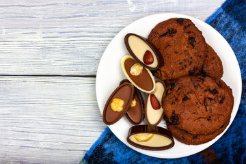 Chocolates and crunchy chocolate chip cookies lie on a white plate. Provence style
