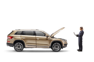 Full length profile shot of a female auto mechanic with a laptop computer checking a SUV