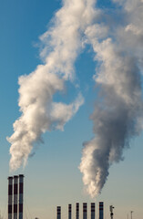the smoke from the chimneys against the blue sky.City thermal power plant