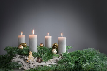 Four candles are burning for the fourth Advent on fir branches with Christmas decoration against a...