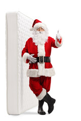 Full length portrait of santa claus leaning on a bed mattress  and showing thumbs up