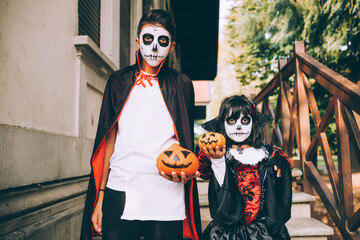 Brother and sister in Halloween costumes with Jack-O-Lanterns