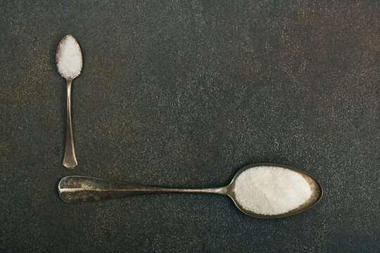 Two spoons of sugar and salt on table