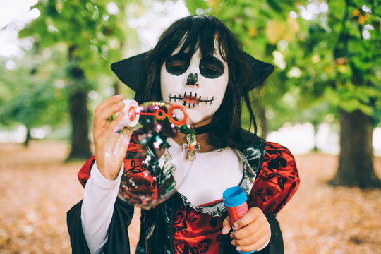 Girl in Halloween costume, blowing bubbles
