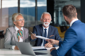 Positive aged couple consulting with insurance agent
