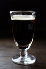 Glass of dark beer on dark wooden background. close up.	