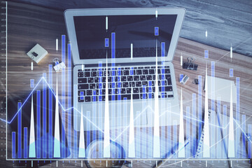 Fototapeta premium Double exposure of financial chart drawing over table background with computer. Concept of research and analysis. Top view.