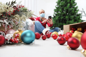 merry christmas, woman wearing surgical mask is forced to stay at home alone due to coronavirus,...