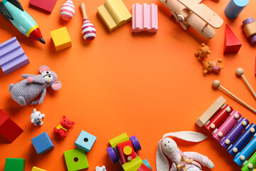 Frame of different toys on orange background, flat lay. Space for text