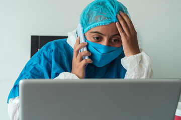 Doctor or nurse wearing a medical face mask to protect against viral diseases by calling on a cell phone in the hospital